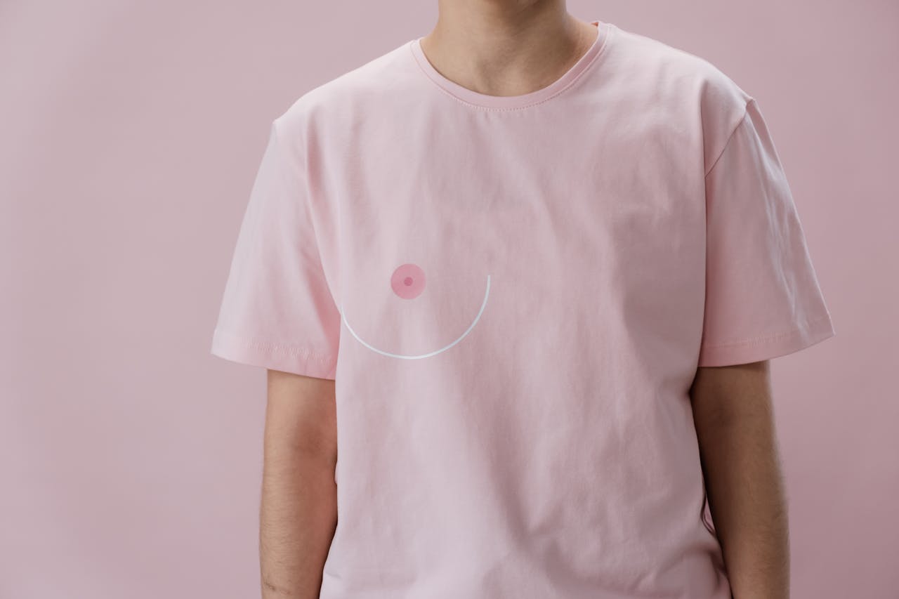 image of womans upperbody wearing a pink t shirt with boob drawn on left side